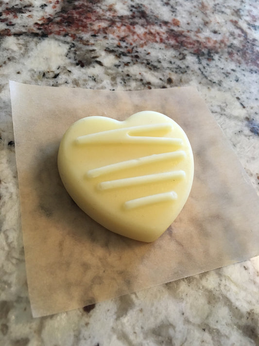 A heart shaped lotion bar on a granite counter.